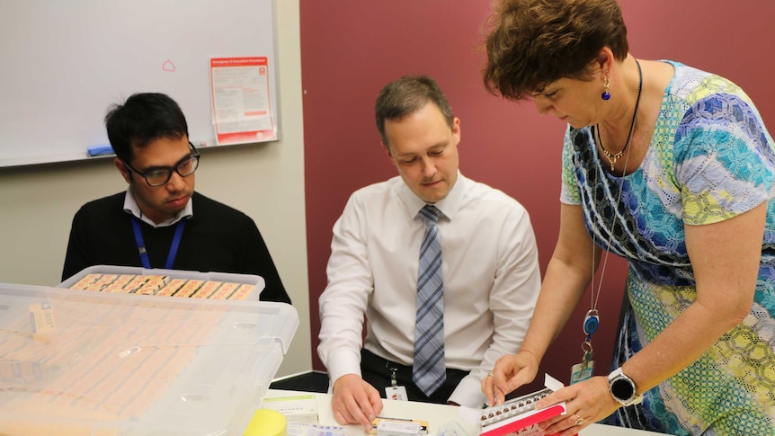 NSW Health investigators Arthur Nguyen, Paul Smith and Kim Dolan examine vials of seized human placenta extract