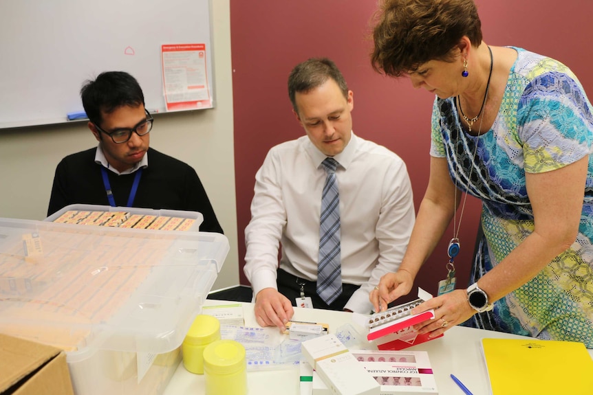 NSW Health investigators Arthur Nguyen, Paul Smith and Kim Dolan examine vials of seized human placenta extract
