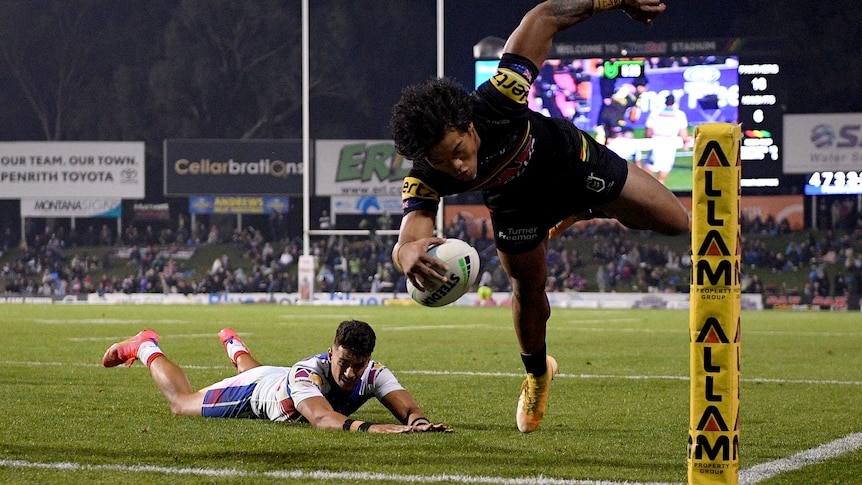 A man scores an acrobatic try in the corner