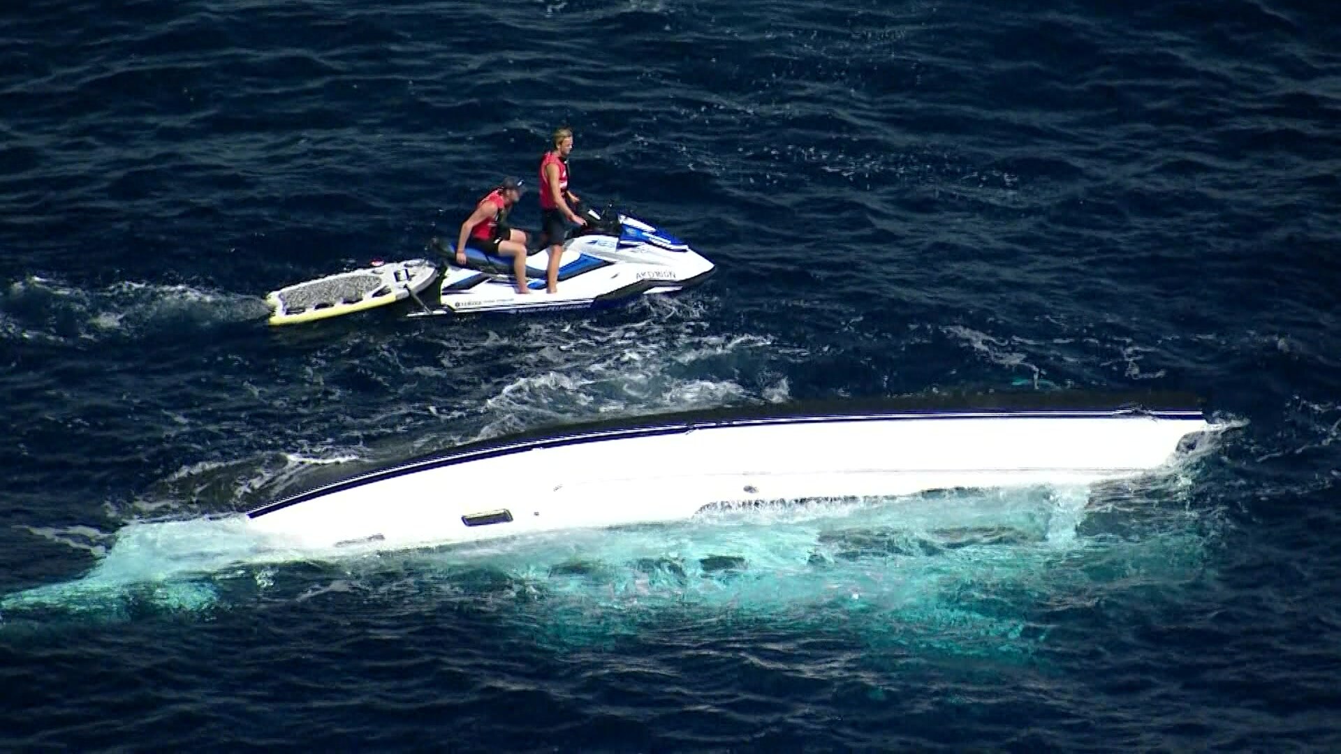 2 men on jetski near sunken boat in the ocean