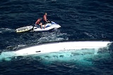 two men on jetski near sunken boat in the ocean