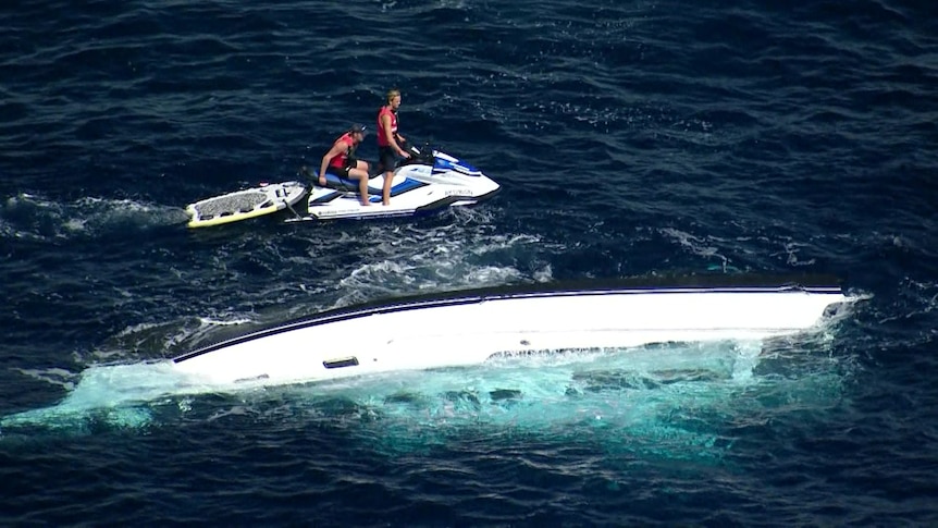 two men on jetski near sunken boat in the ocean