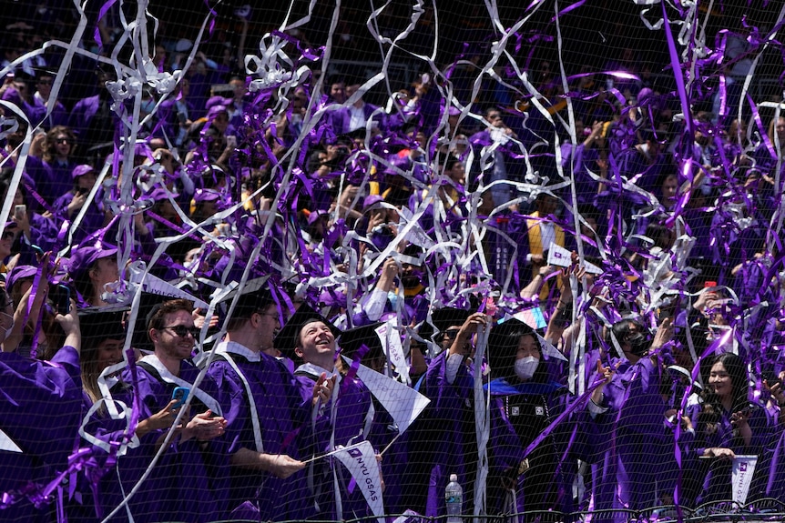 Confetti drops on graduates as they celebrate during a graduation ceremony.