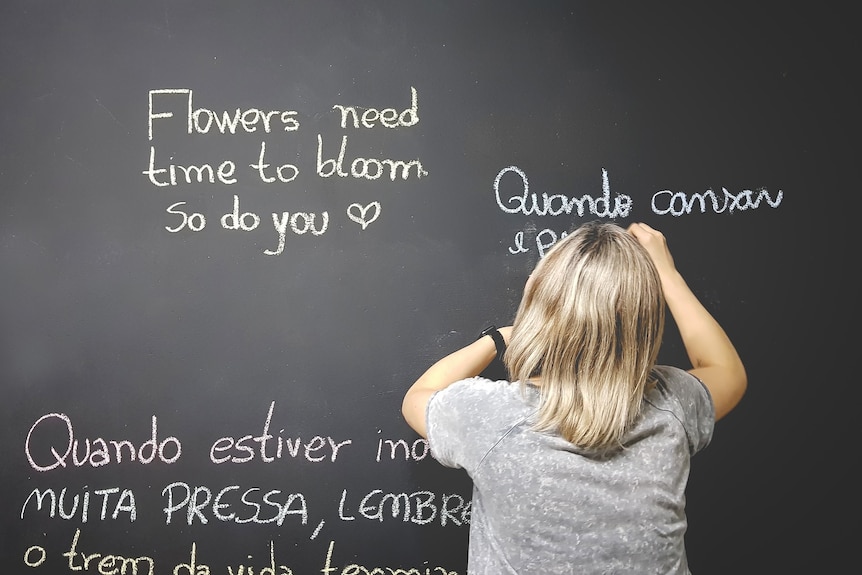A child in a grey shirt writing on a blackboard