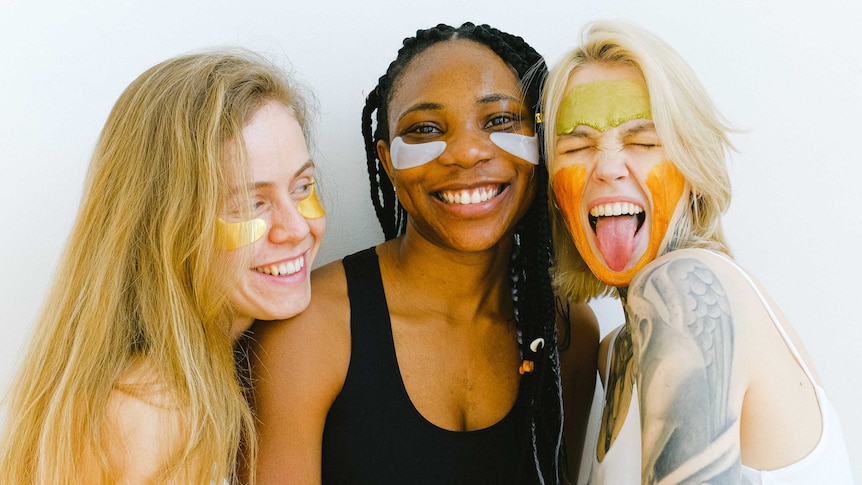 Three women with face masks laughing in a story about a bare minimum skincare routine for those on a budget.