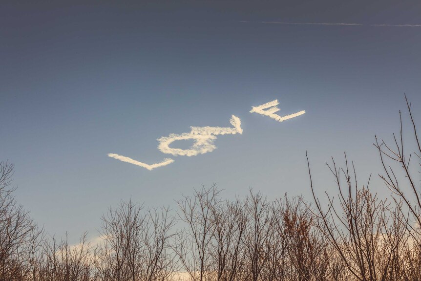 The word 'love' is skywritten in block letters, as seen from an RV park outside New Orleans.