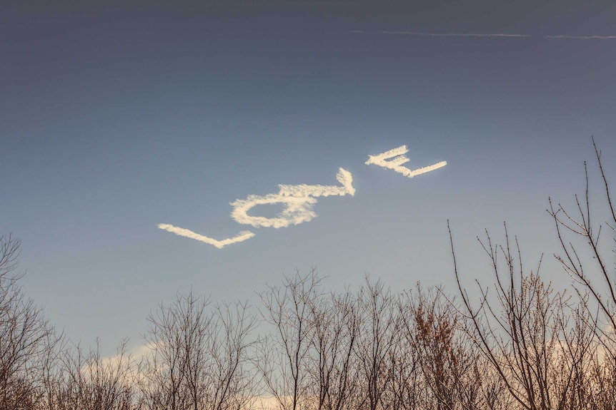The word 'love' is skywritten in block letters, as seen from an RV park outside New Orleans.
