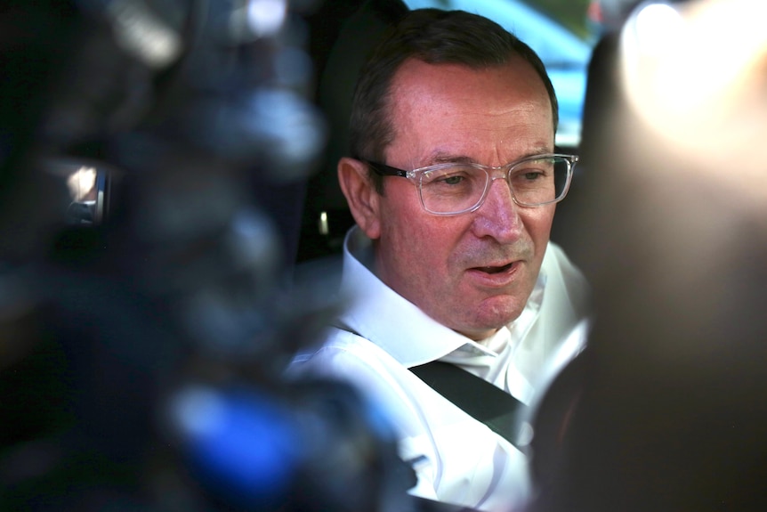 Mark McGowan pictured in between cameras pointed at him through his car window