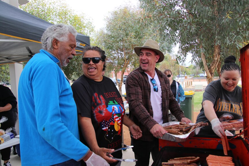 A side shot of  Ernie Dingo and three other people cooking a barbecue 