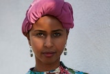 A woman wearing a pink headscarf.