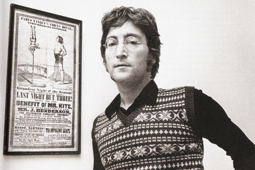 John Lennon stands next to the poster than inspired Being for the Benefit of Mr Kite.