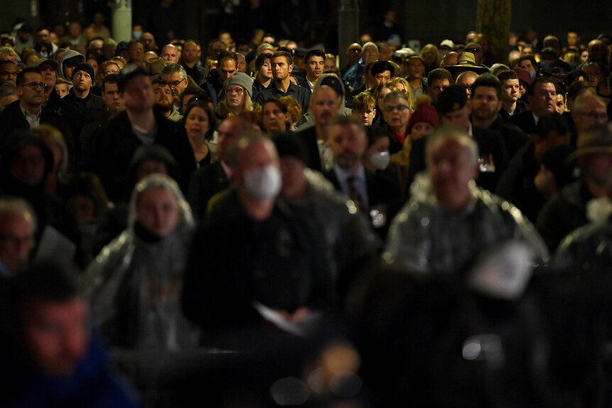 A large crowd of people, many in wet-weather gear, gather for the Anzac Day dawn service in Sydney's Martin Place.