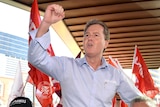 A man at the centre of a flag waving crowd sits on people's shoulders cheering