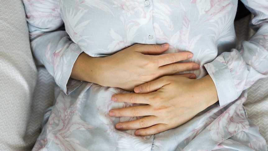 Woman clutches her abdomen in pain.