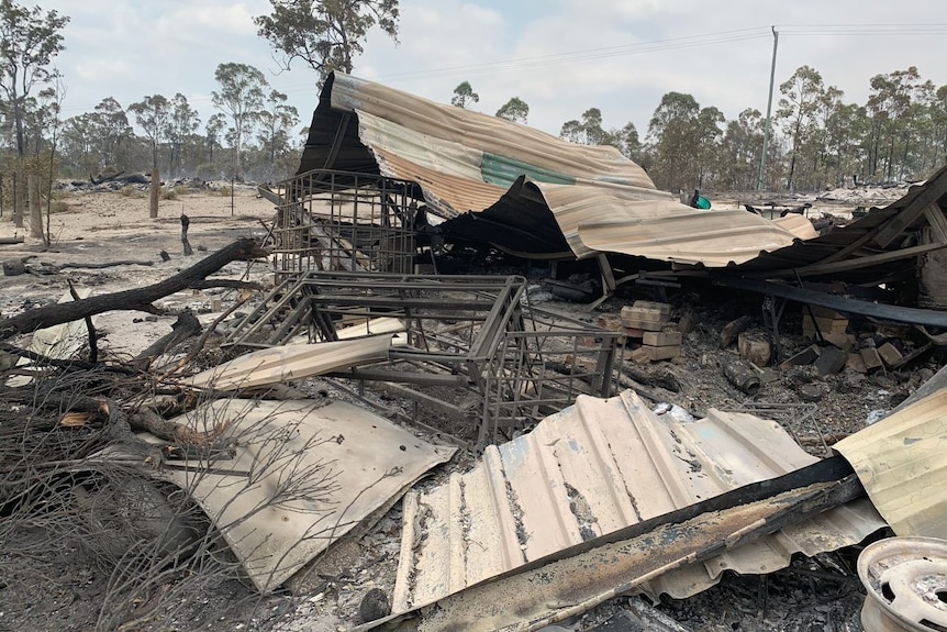 A house destroyed by fire. The roof is crumpled, burnt wires are twisted and bricks lay scattered