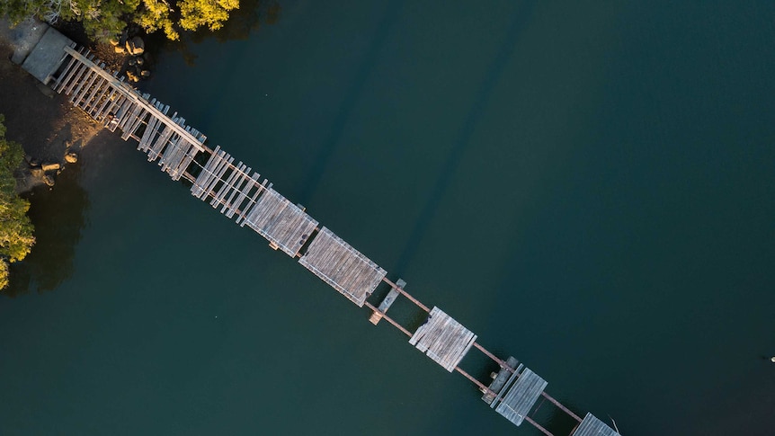 Rickety bridge over river with missing planks