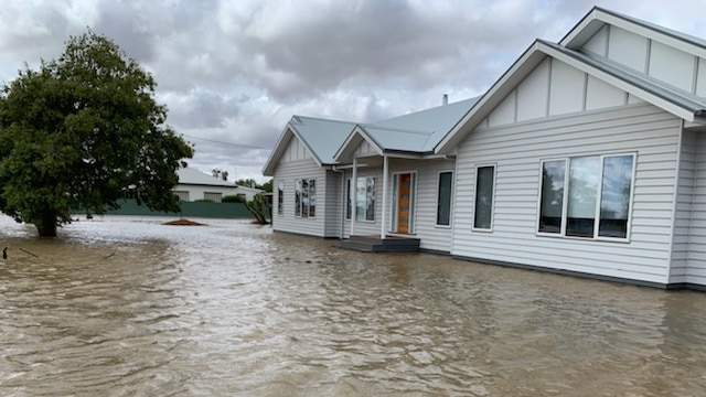 Muddy waters have risen to the bottom step of a house verandah.