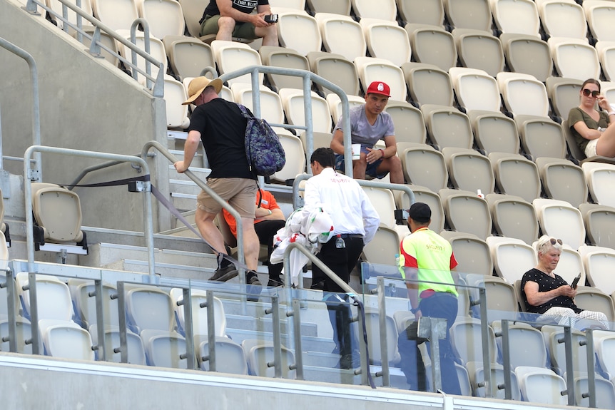 Spectators are escorted from the stadium by security at the Australia vs Pakistan Test in Perth.