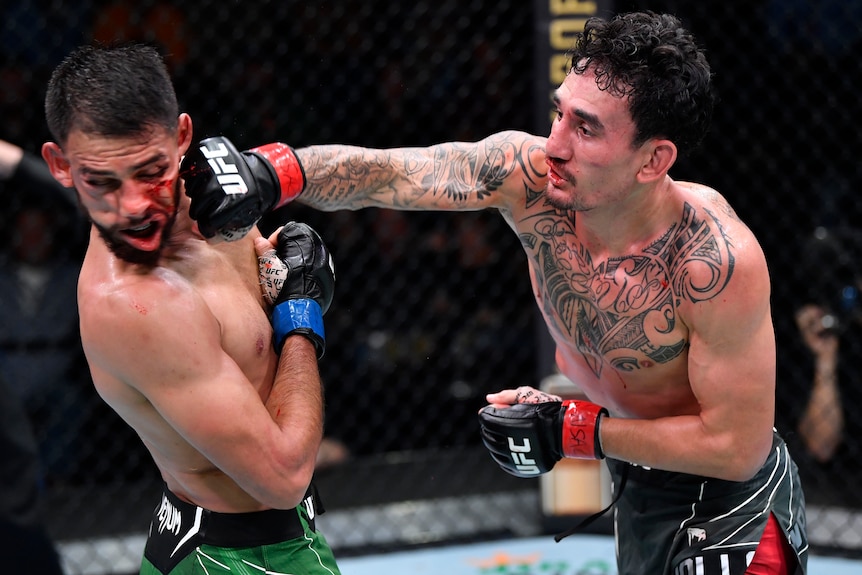 A male UFC featherweight fighter punches an opponent with his right fist during a bout.