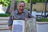 A man standing holding an photo album