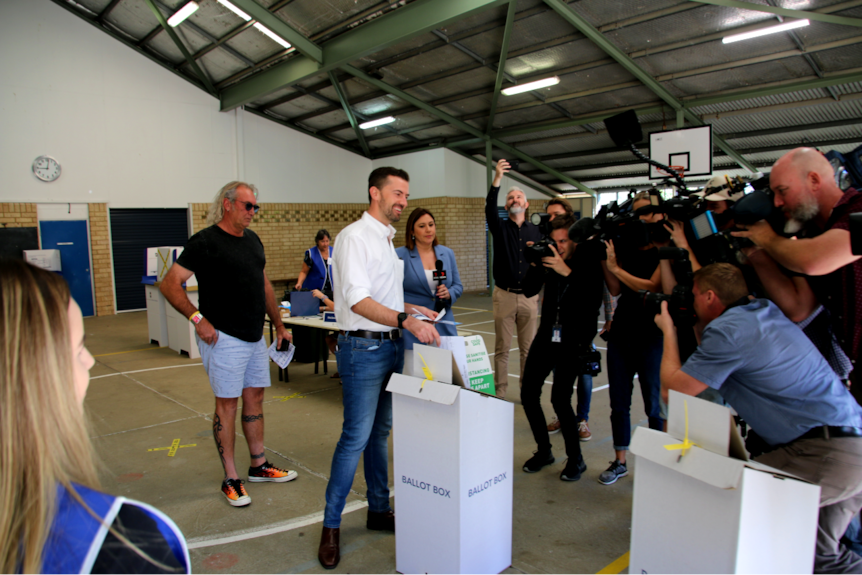 Zak Kirkup votes in front of a bank of camera operators and reporters.