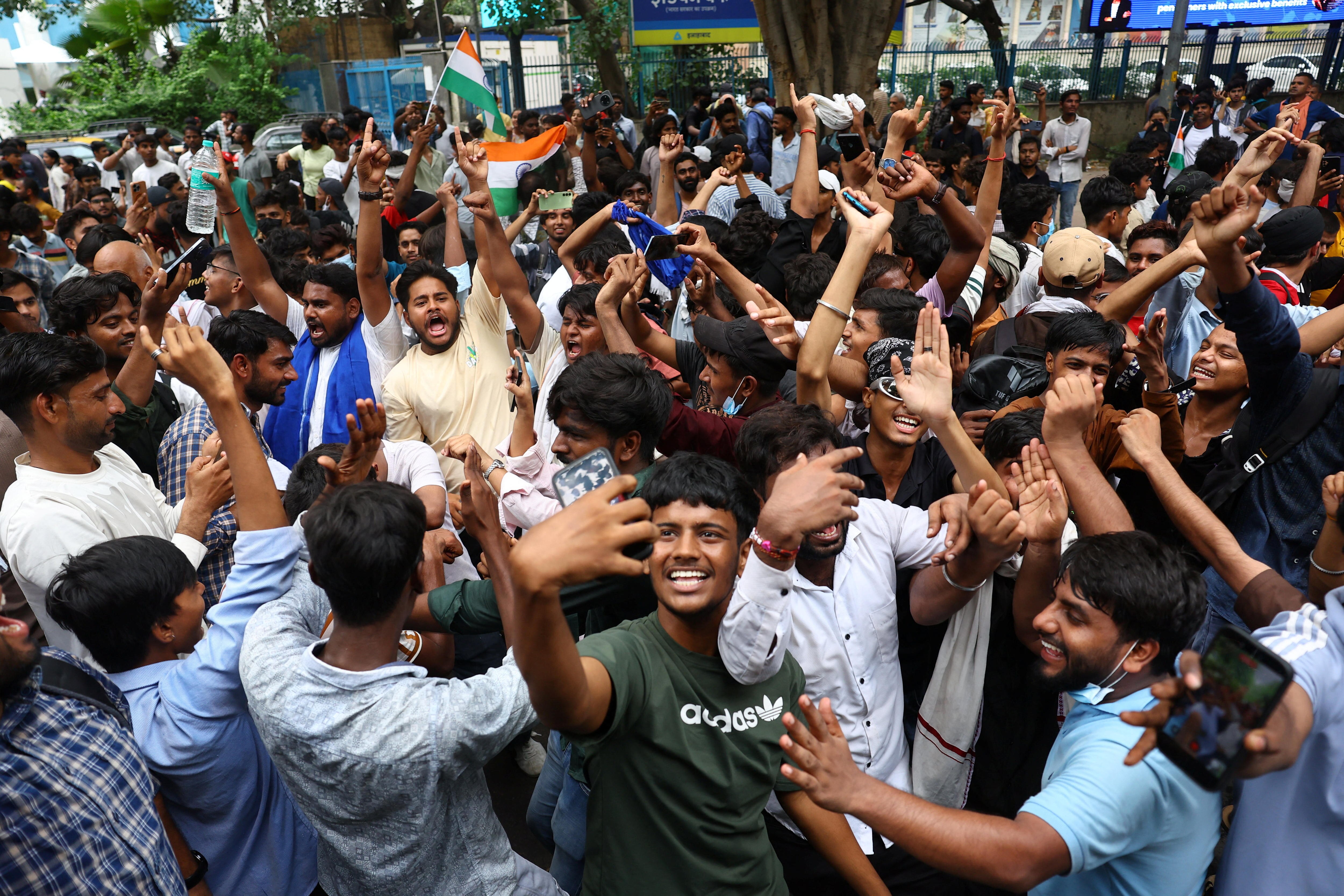 A large crowd wave their arms in the air in celebration, holding flags and phones