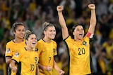 Matildas players cheer reacting to a penalty shoot out in a large stadium