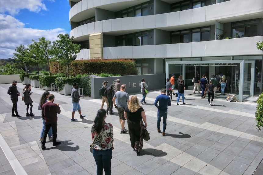 People standing outside apartment building. 