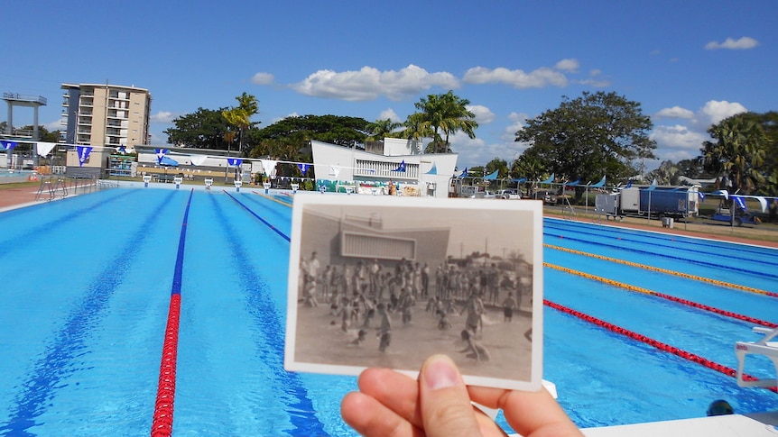 An old photo shows a packed Rockhampton pool with the same building in the background as the one in the photo.