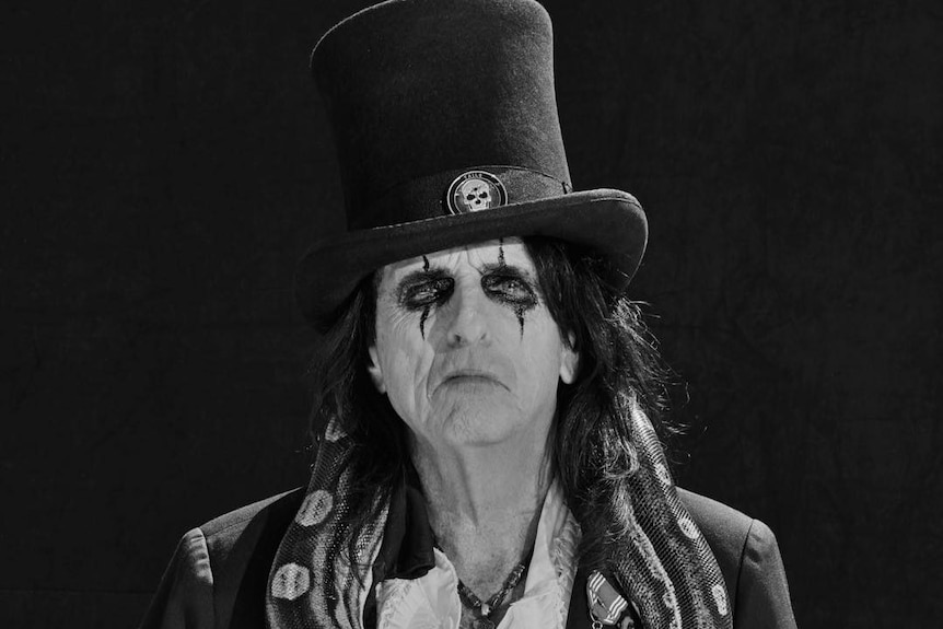 Black and white image of Alice Cooper wearing make up and a top hat
