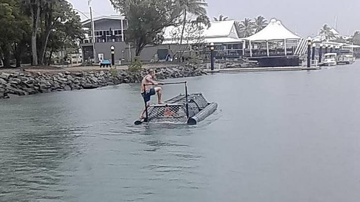A man standing on top of a crocodile trap at the Port Douglas marina.