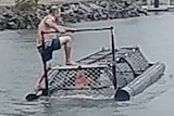 A man standing on top of a crocodile trap at the Port Douglas marina.
