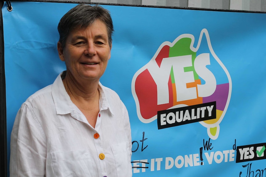 Maxine Drake stands in front of a sign that says "Yes equality".