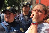 A woman cries as she stands alongside authorities at the site of the collapsed Mexico City School.