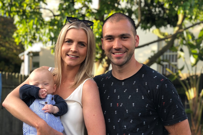 a mum and dad smiling while holding their infant son