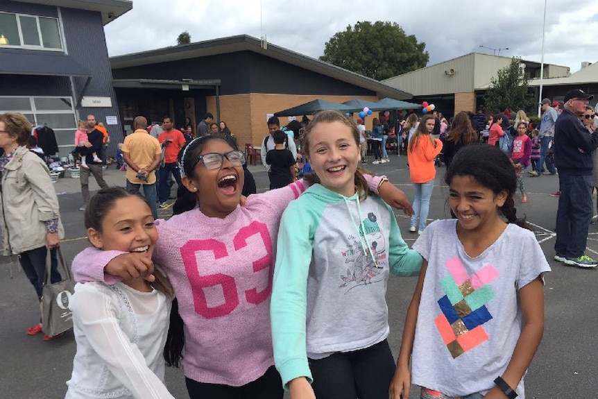 Girls stand with their arms around each other, laughing