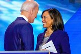 Joe Biden and Kamala Harris smile at each other while shaking hands