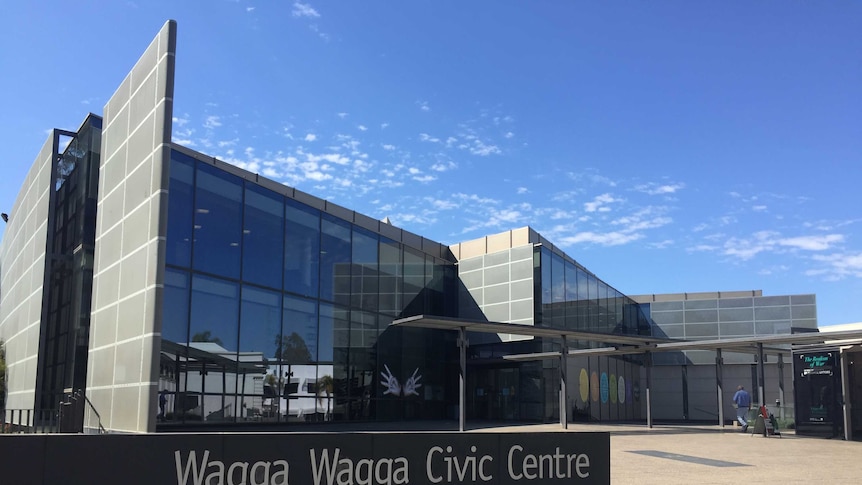 Wagga City Council Civic Centre featuring sign in left forefront and backdrop of council building with person about to enter