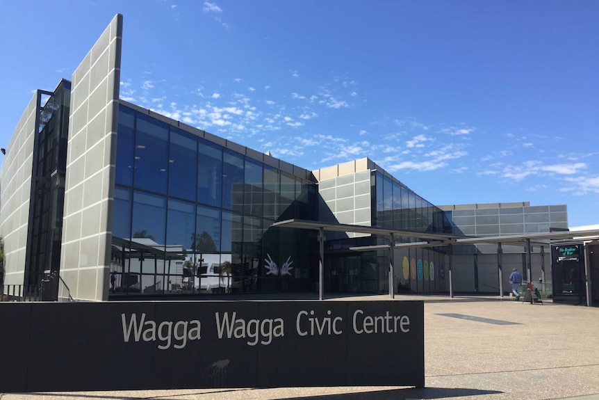 Wagga City Council Civic Centre featuring sign in left forefront and backdrop of council building with person about to enter