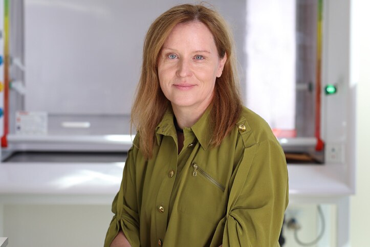 Professor Eva Bezak wearing a green stop standing in a university room with a white board in the background.