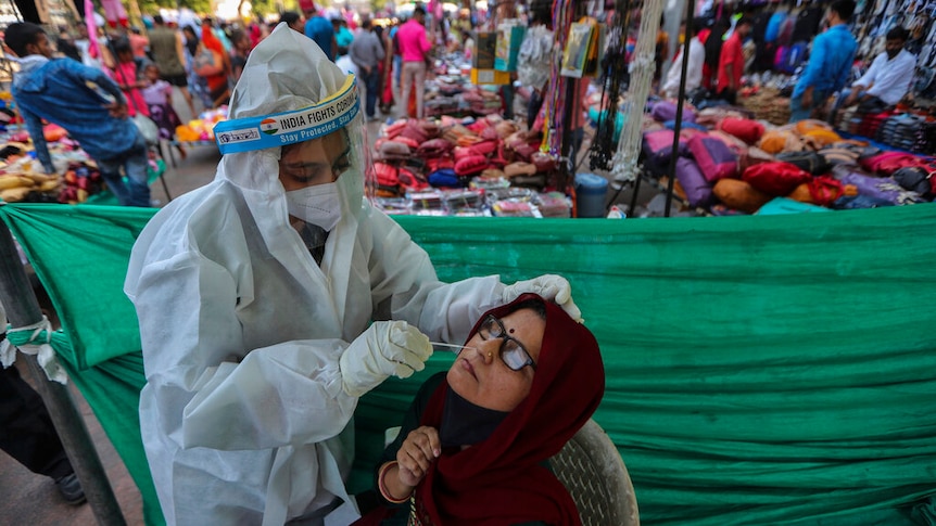 A health worker takes a nasal swab sample of a woman to test for COVID-19 at a facility erected in a market in Ahmedabad.