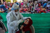 A health worker takes a nasal swab sample of a woman to test for COVID-19 at a facility erected in a market in Ahmedabad.