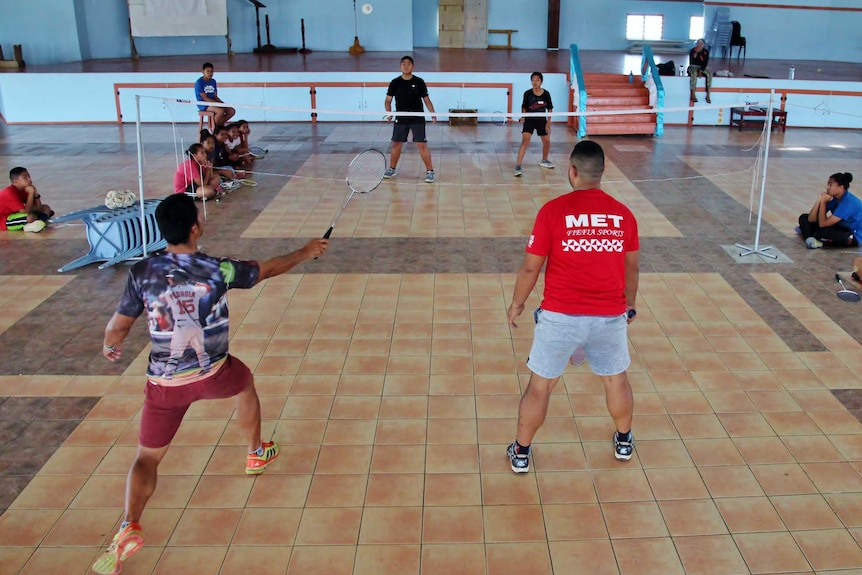 Tevita and young players contest a point on a court inside a school hall