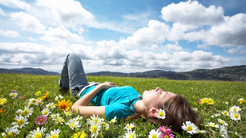 A woman lying in the grass on a sunny day.