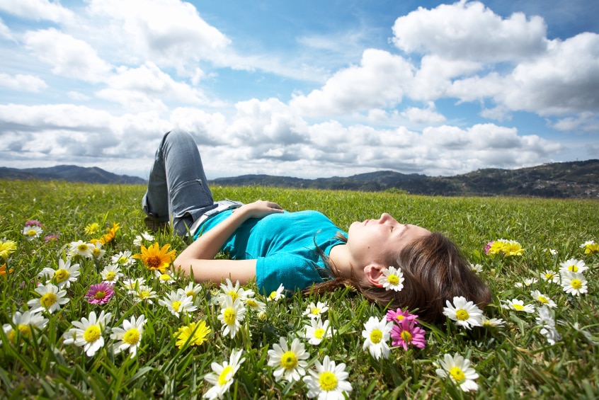 A woman lying in the grass on a sunny day.