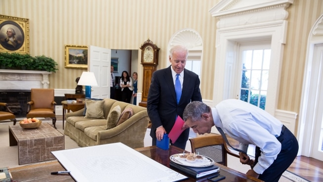 President Barack Obama blows out candles on birthday cupcakes brought to him by Joe Biden