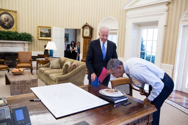 President Barack Obama blows out candles on birthday cupcakes brought to him by Joe Biden