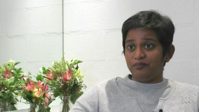 Author Shamini Flint sits beside flowers