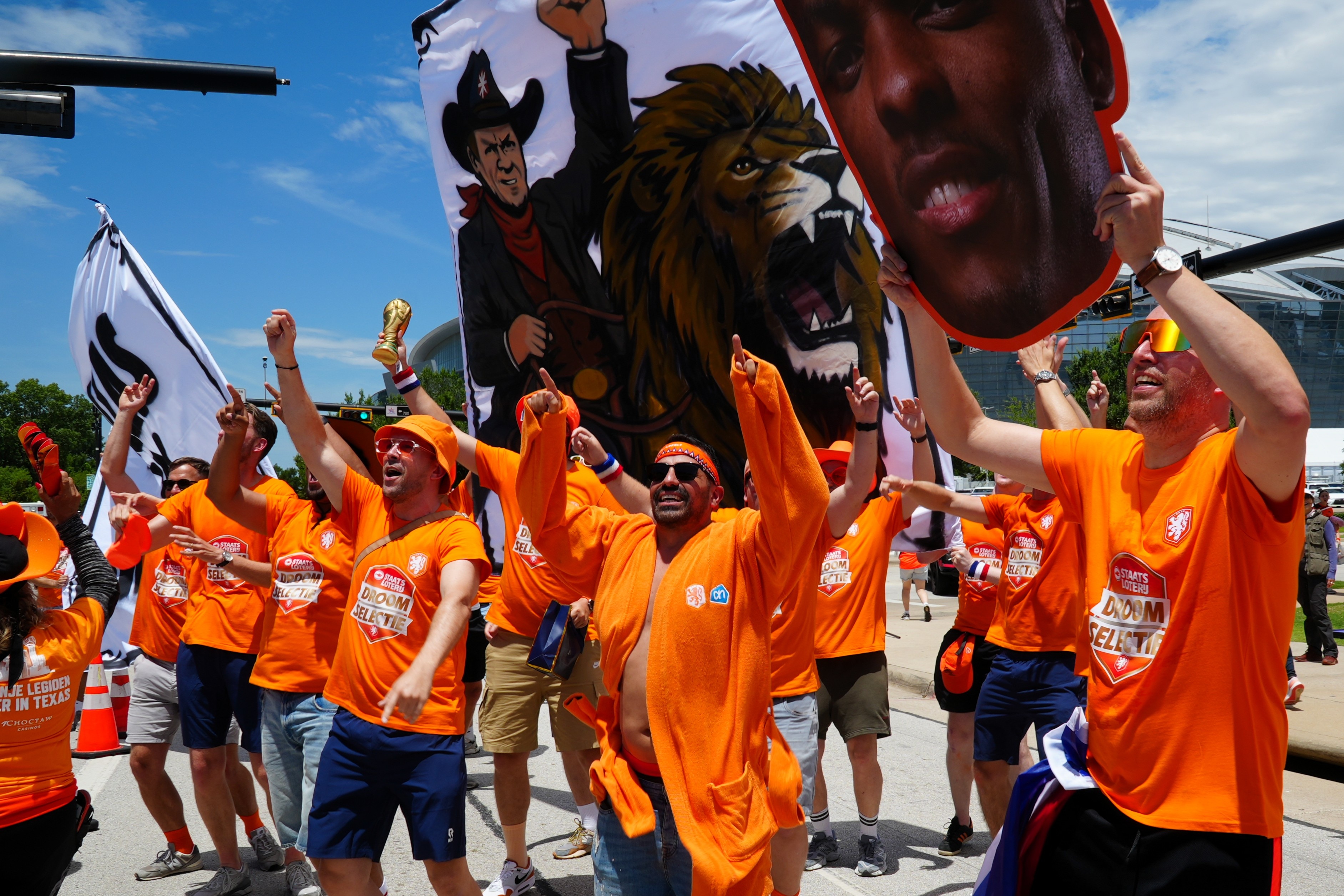 A group of male Dutch football fans dressed in orange, cheering