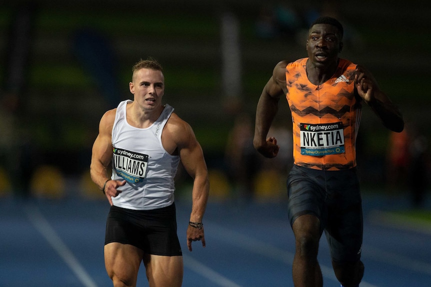 Two runners strain as they sprint down the track in the 100m at Australian Track and Field titles.